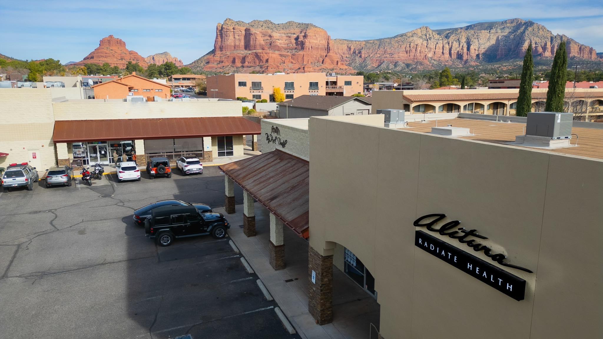 Parking lot with cars in front of a building, with mountains in the background.