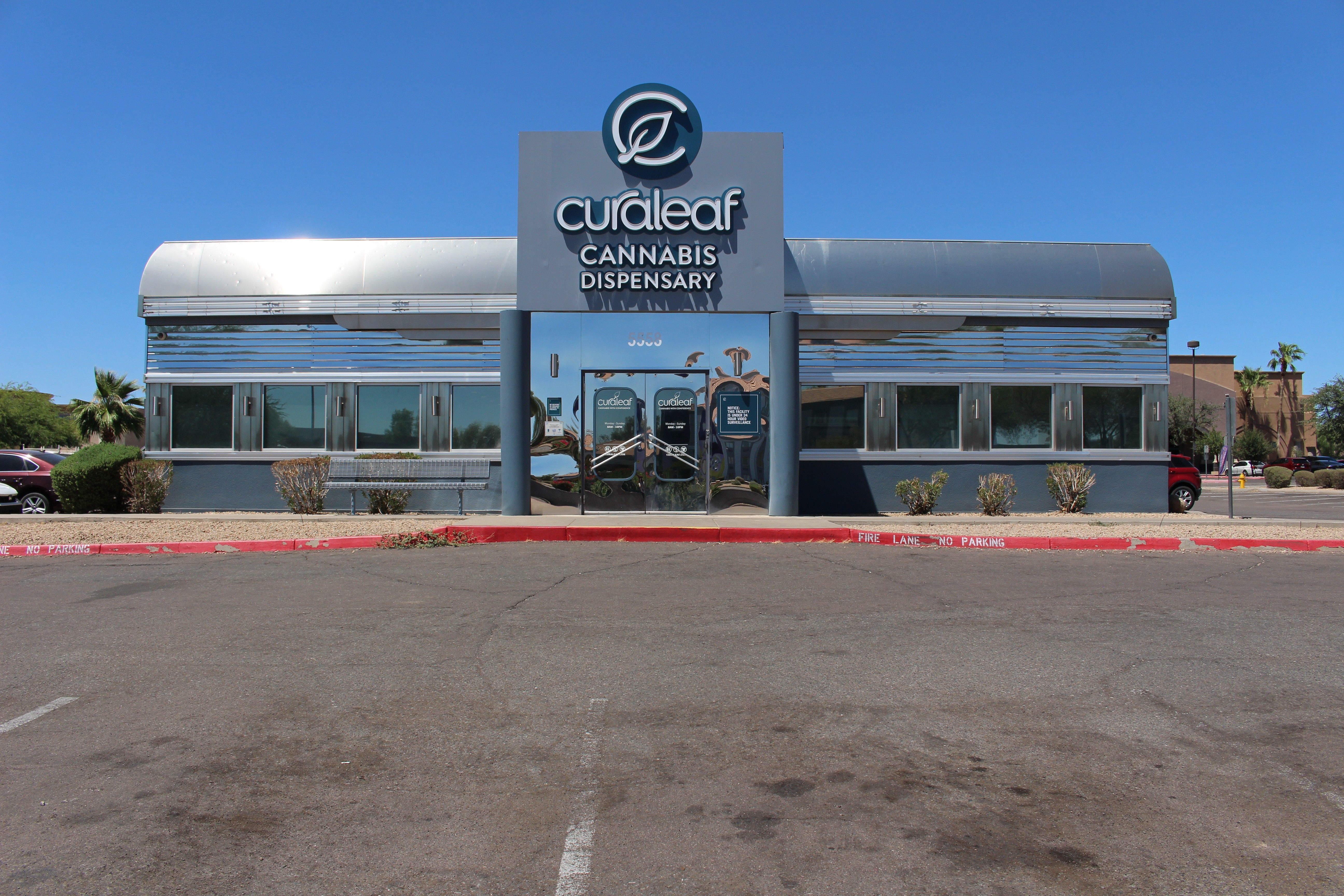 Cannabis dispensary building with a sign reading 'Cureleaf Cannabis Dispensary' against a blue sky, with a parking lot in front.