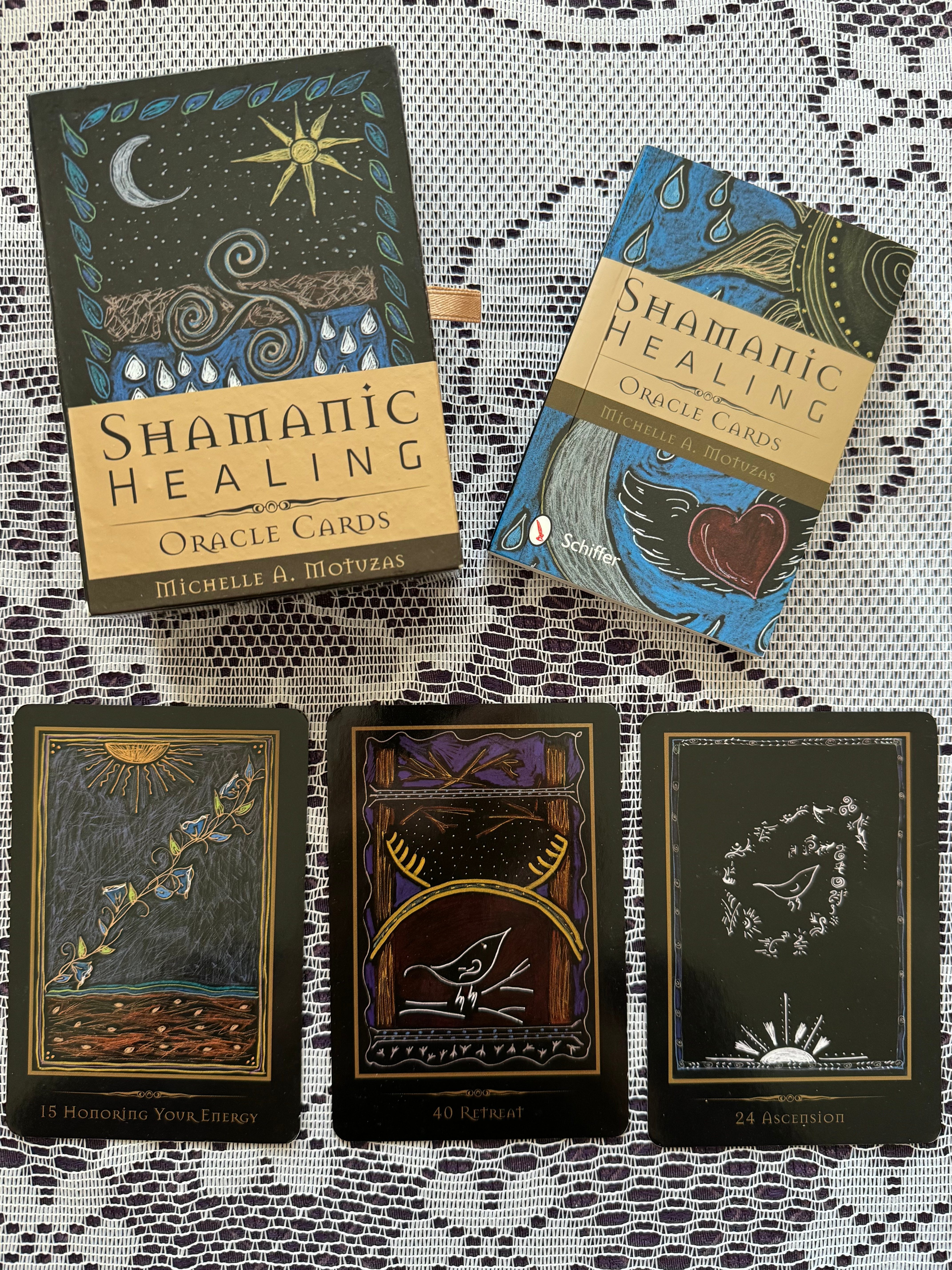 Three tarot cards and a book on a lace tablecloth, with the book titled 'Shamanic Healing' by Omraam Mikhaël Aïvanhov.