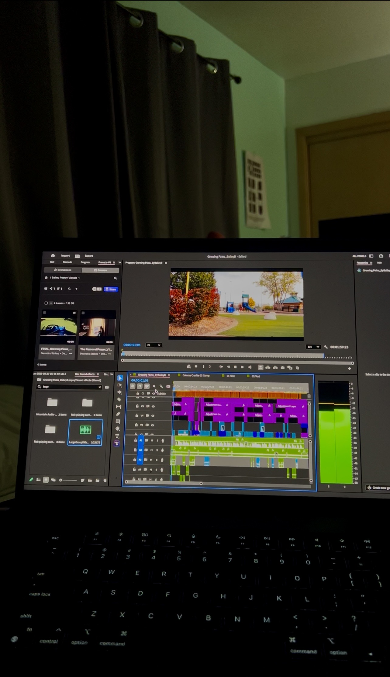 Laptop screen displaying video editing software with colorful timeline and preview window, in a room with dark curtains and green wall.