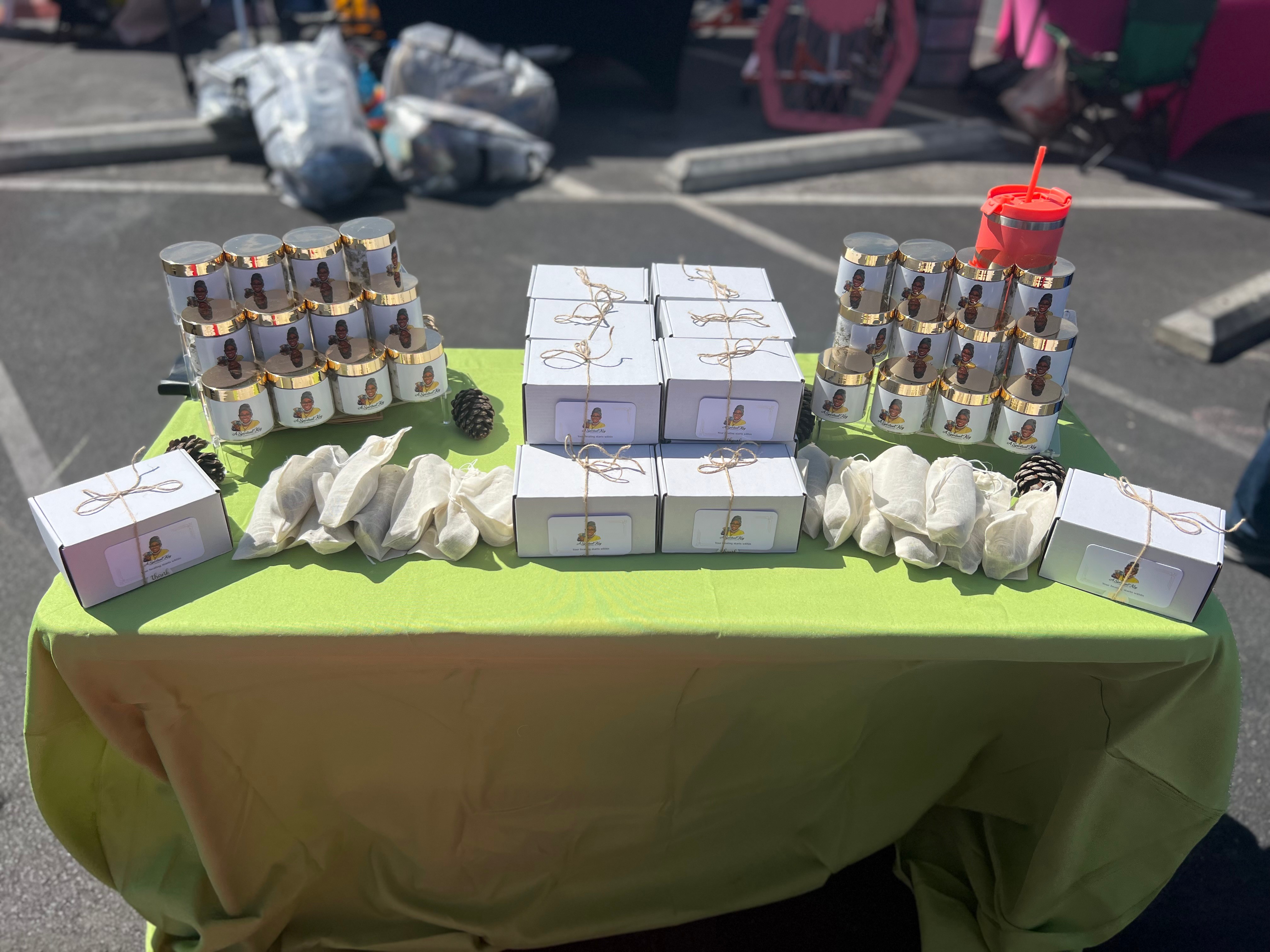 Table with boxes, cans, and a red candle holder, set outdoors on a sunny day.