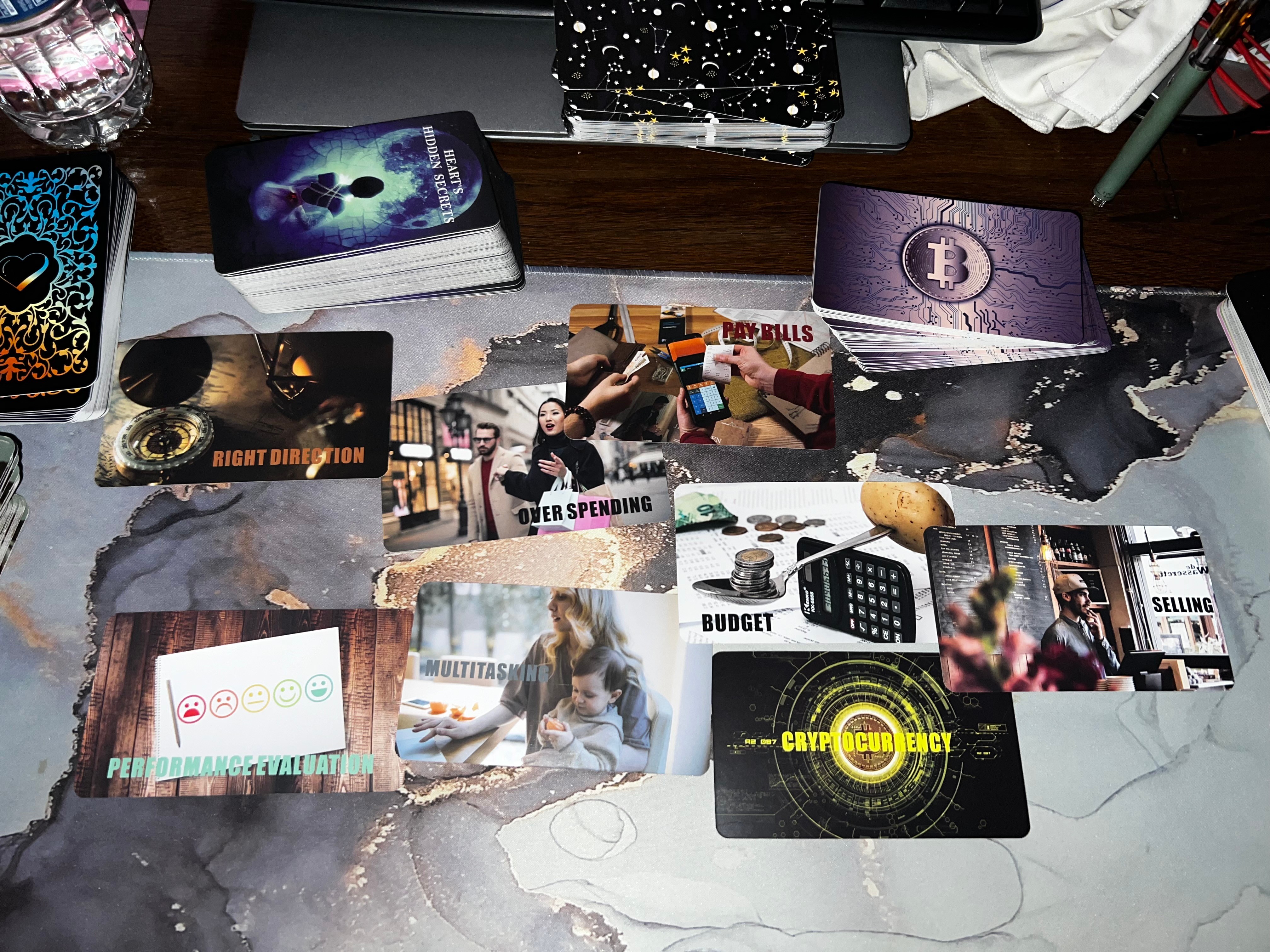 Various cards and photographs spread on a table, including a book, a purple card, and a black card with yellow text.