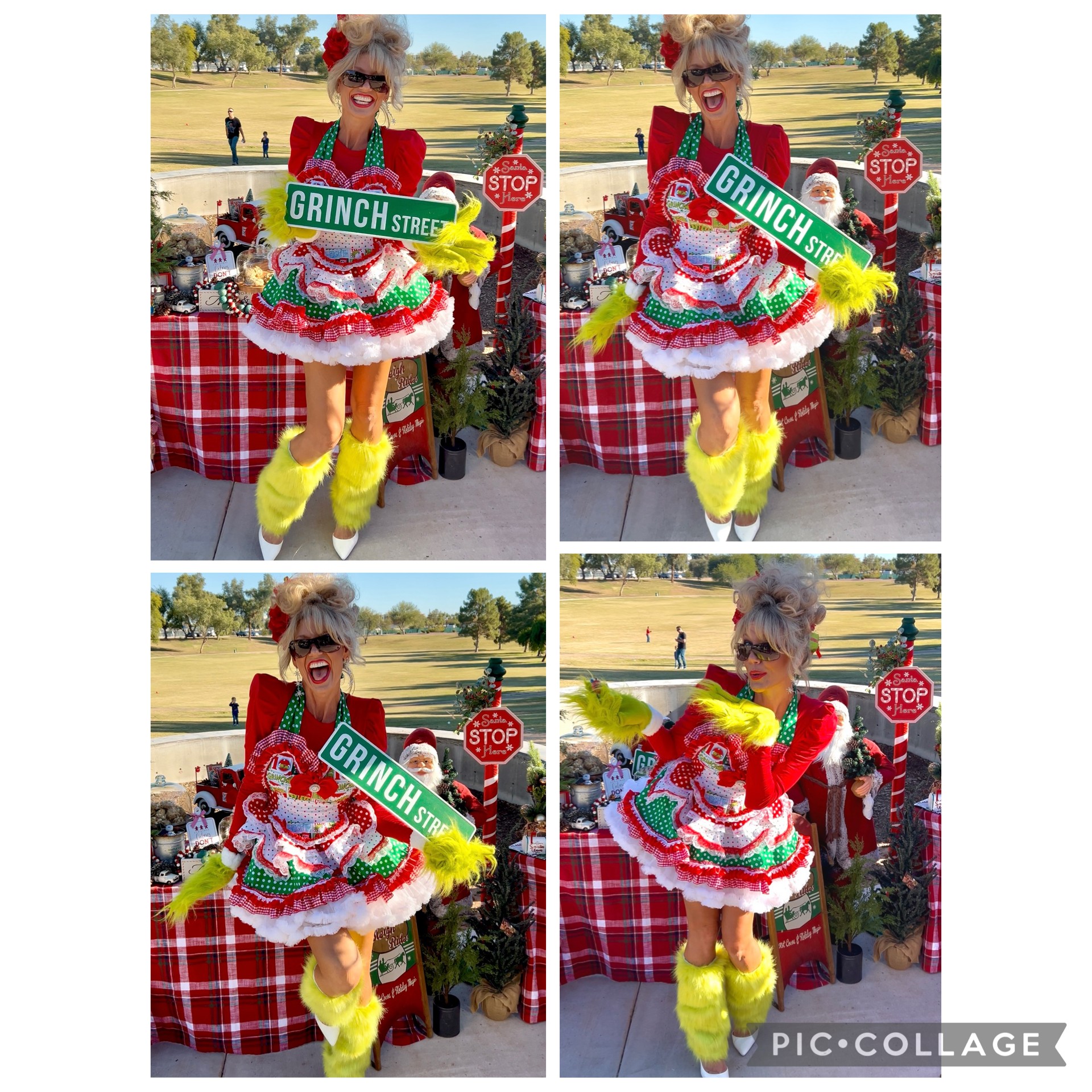 Person dressed as a colorful Christmas tree with a sign, yellow boots, and sunglasses, standing outdoors near a table with a red checkered tablecloth.