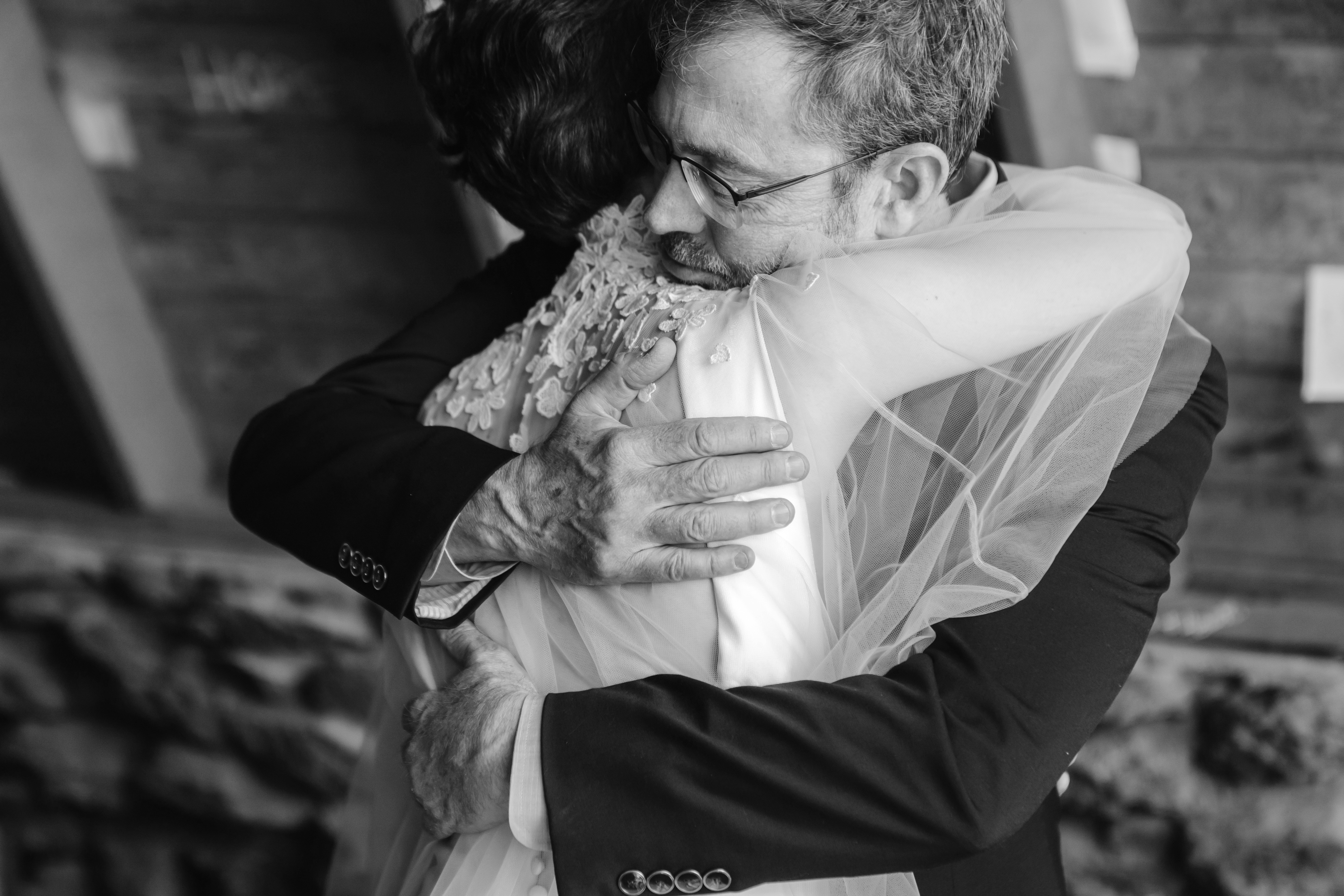 Two people hugging, one wearing a wedding dress, in black and white, emotional moment, close-up, indoor setting