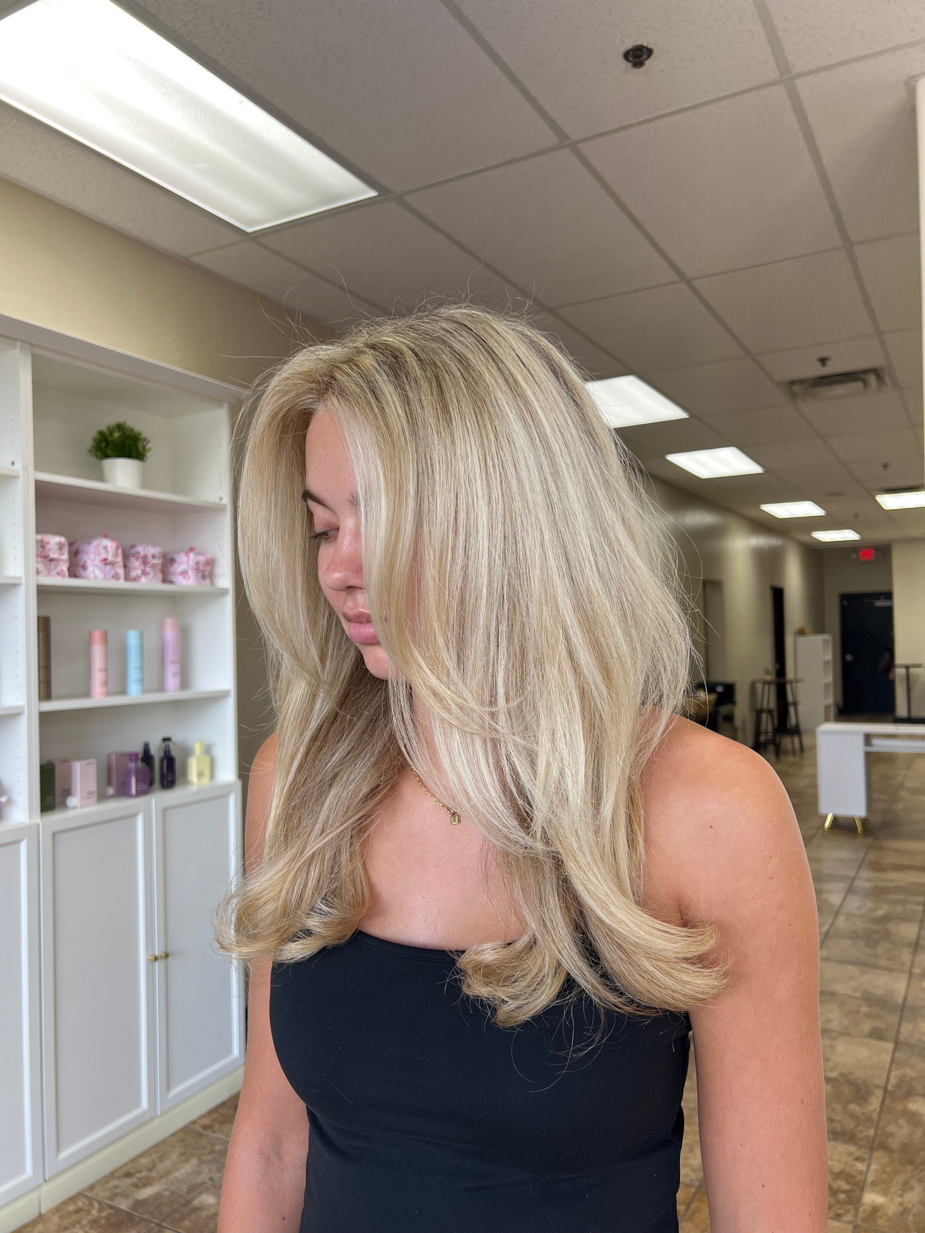 Woman with blonde hair looking down in an indoor setting with white cabinets and ceiling lights.