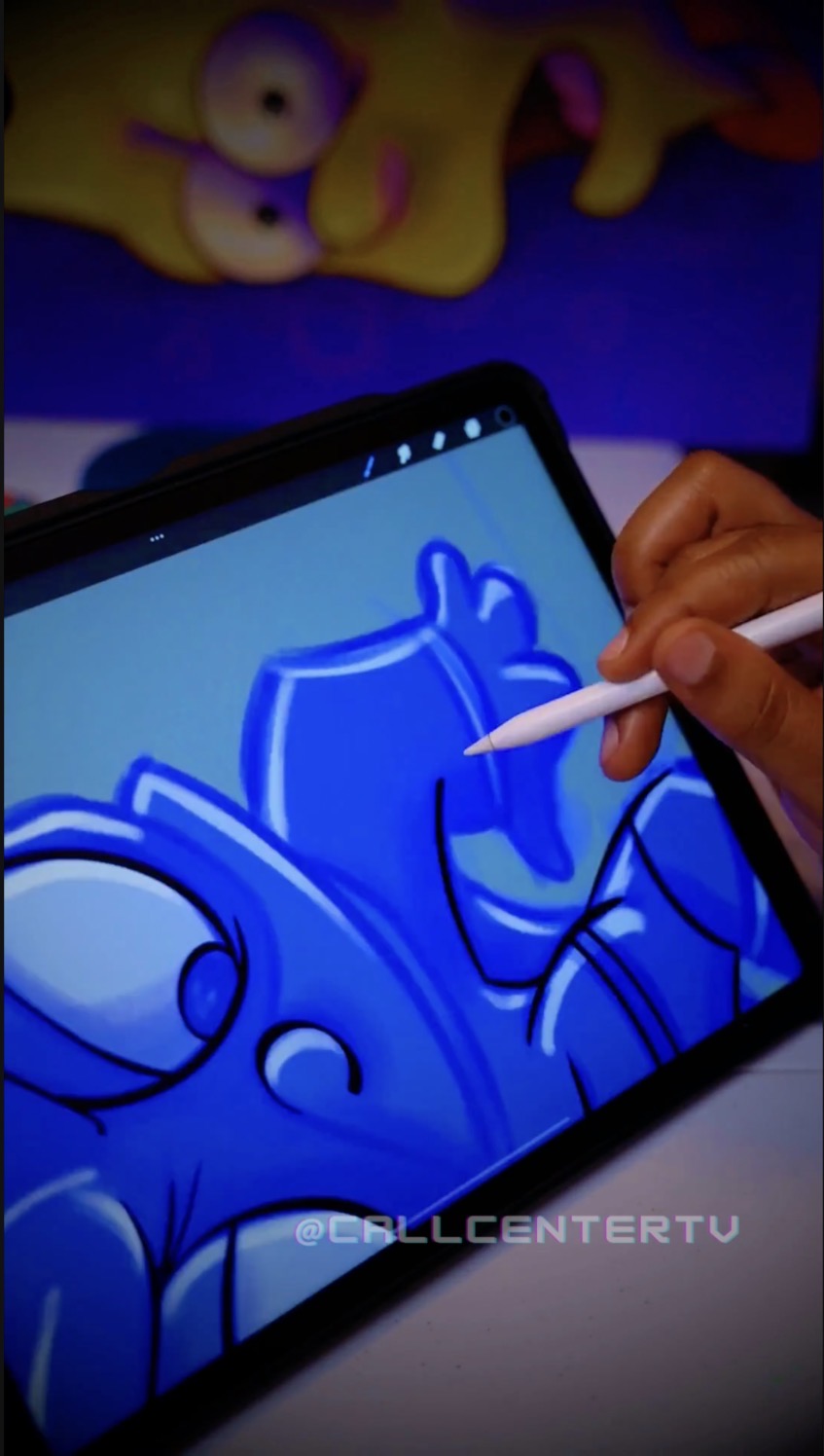 Person drawing a blue cartoon character on a tablet with a stylus, with a yellow cartoon character in the background.