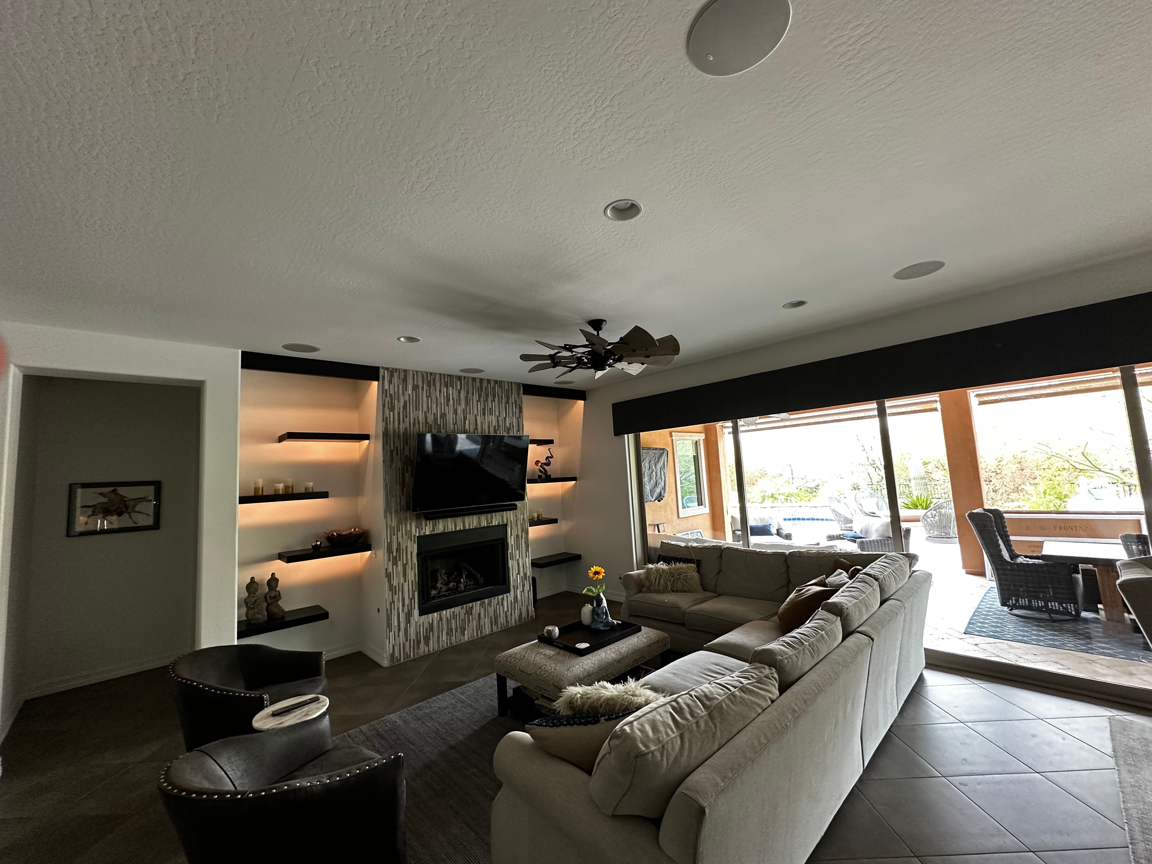 Living room with large sectional sofa, fireplace, TV, and large windows with outdoor view.