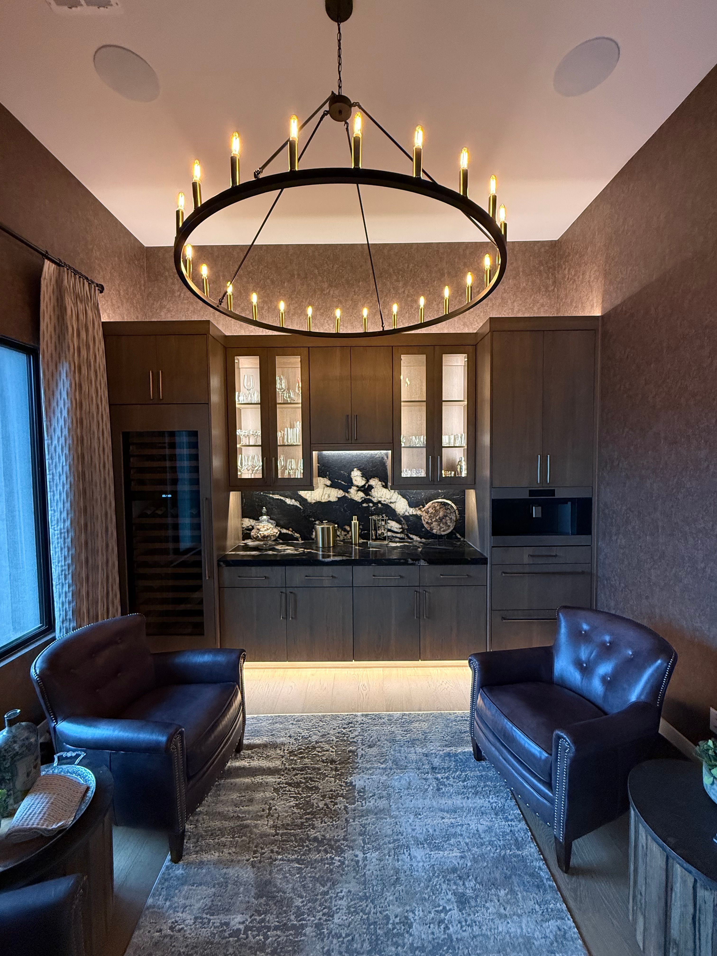 Living room with a circular chandelier, dark furniture, and a large window with curtains.