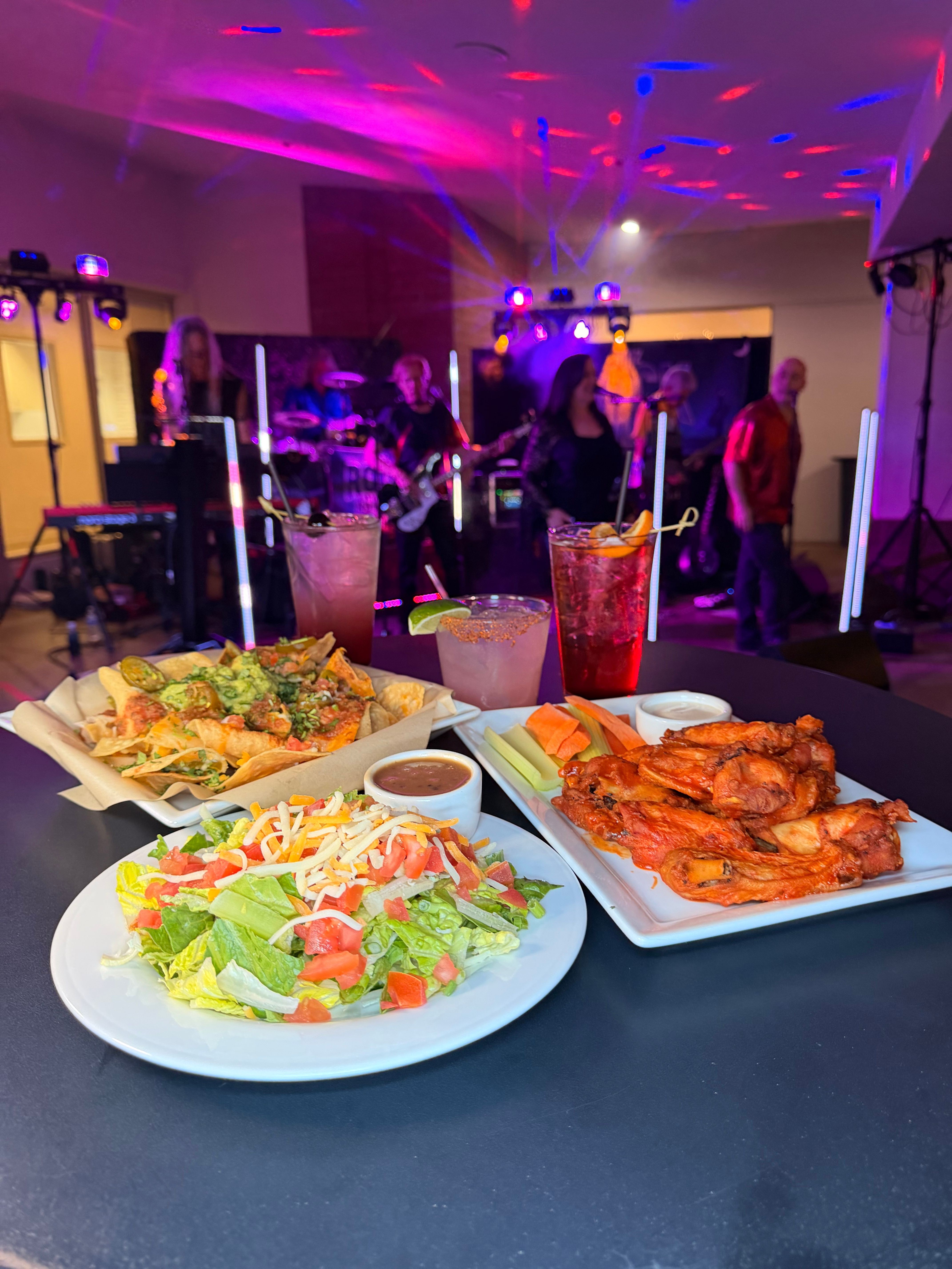 Two plates of food, one with fried chicken and vegetables, the other with a salad, on a table at a party.