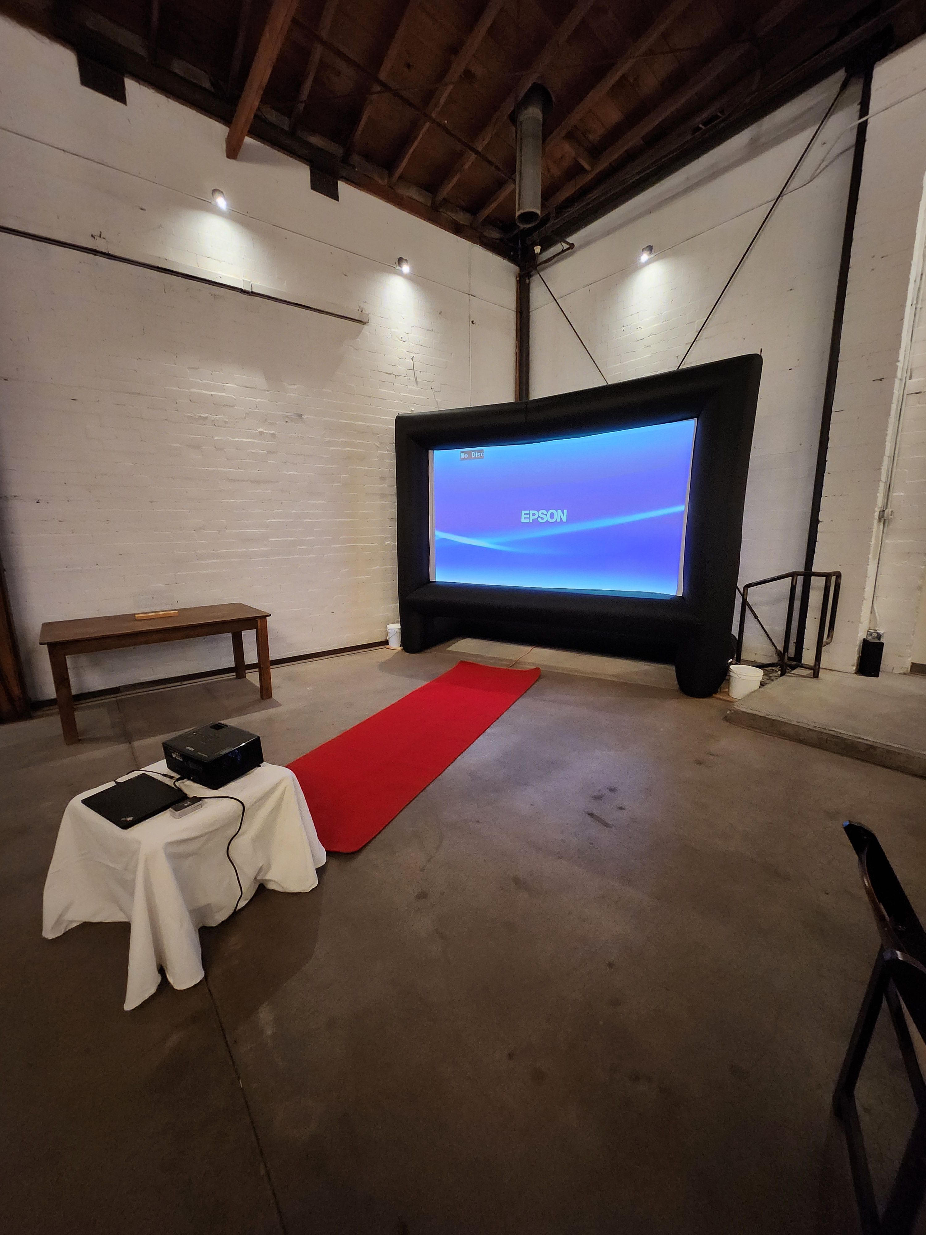Television screen displaying a blue background, red carpet, and a white cloth-covered object on the floor.