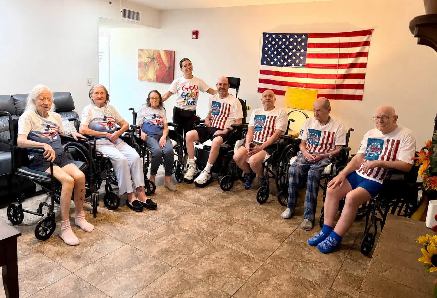Group of elderly people in a room with an American flag on the wall, some holding small American flags, smiling.