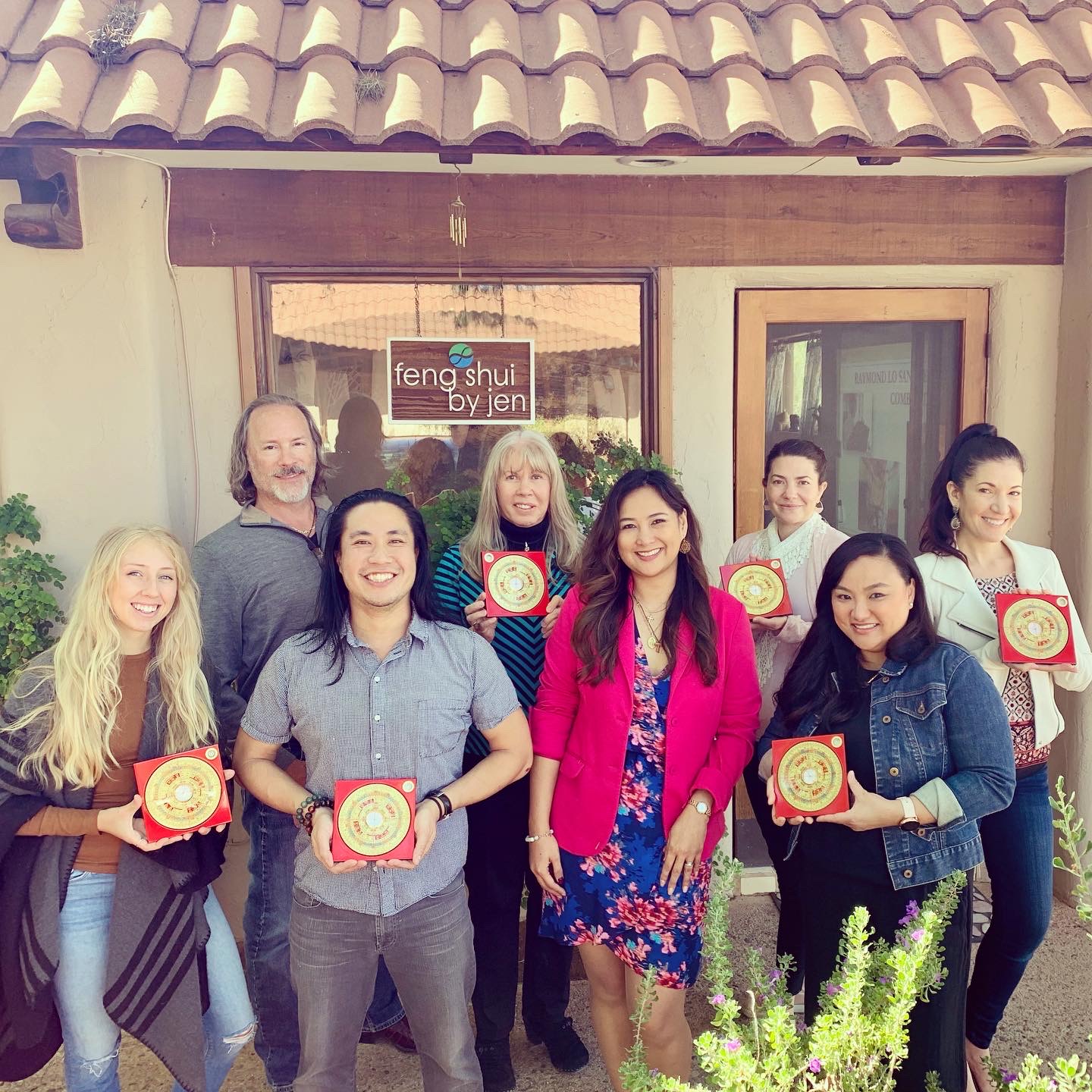 Group of eight people standing outside a building, holding awards, smiling, with a sign that reads 'feng shui by jen' behind them.