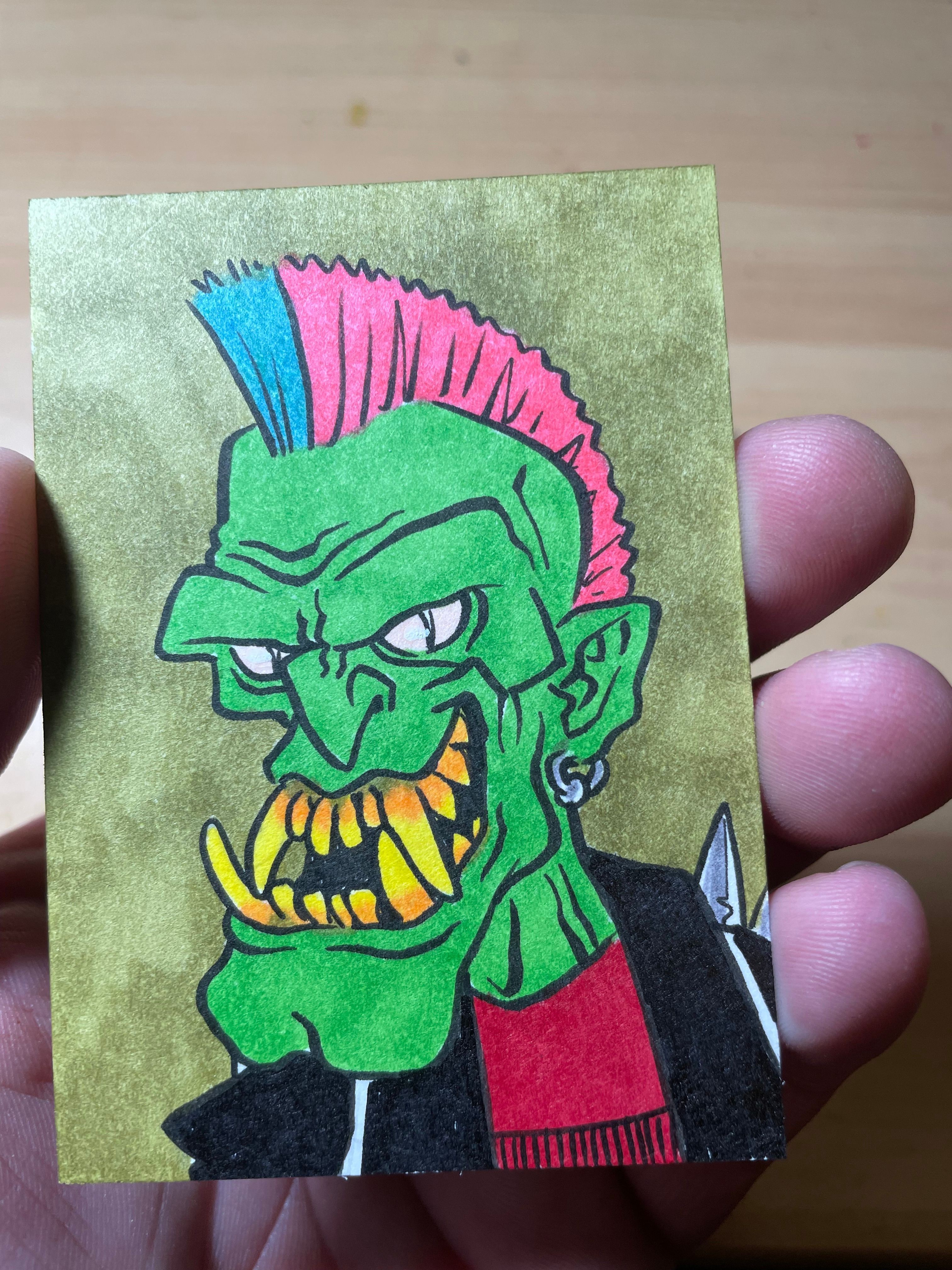 Colorful drawing of a green creature with pink hair and a yellow-striped tongue, holding a small yellow object.