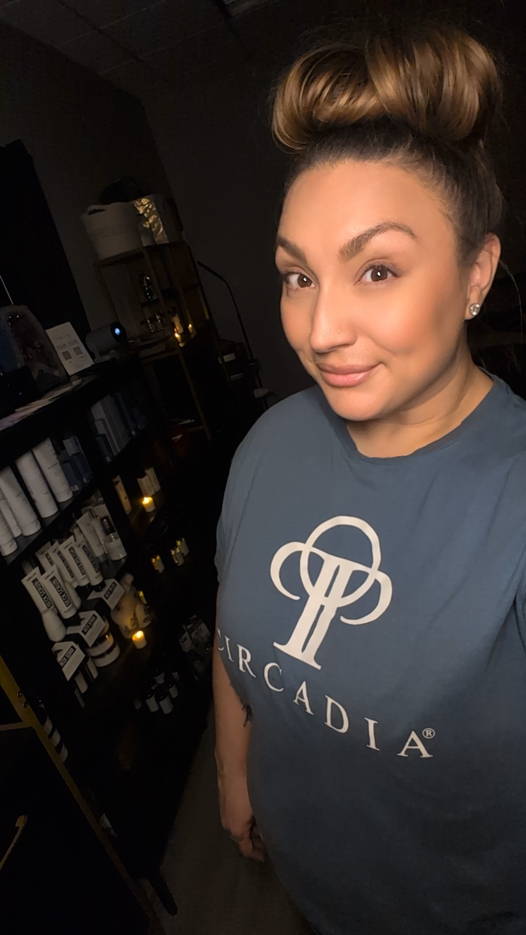 Woman with styled hair wearing a blue shirt with a logo, smiling at the camera.